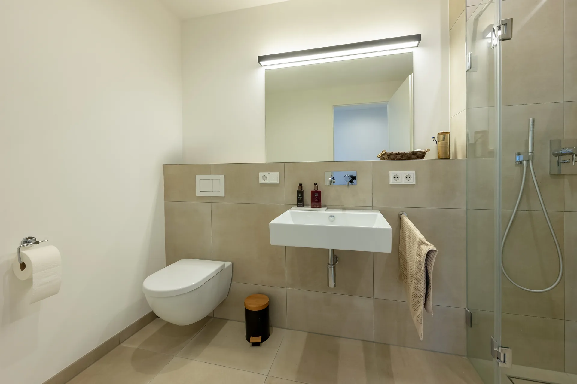 Modernes Badezimmer mit bodengleicher Dusche, Designspiegel und hochwertigen Armaturen im Lifestyle-Apartment