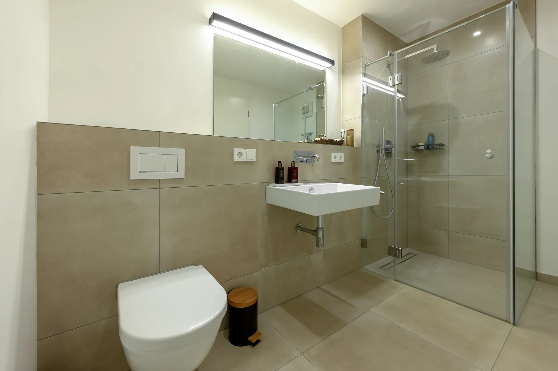 Großzügiges Badezimmer mit ebenerdiger Dusche und Natursteinoptik-Fliesen im Lifestyle-Apartment Mönchengladbach