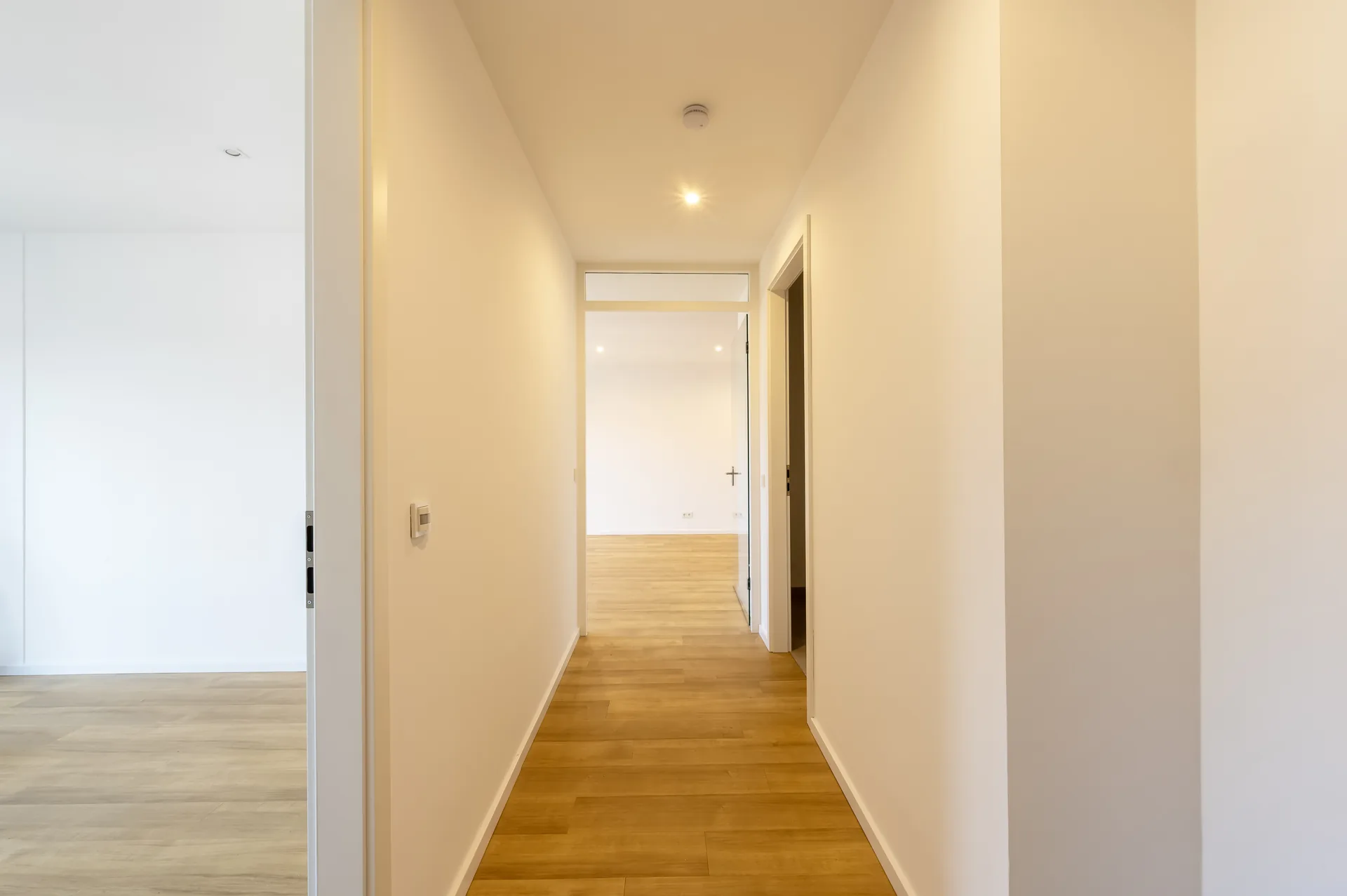 Heller langer Flur mit Parkettboden im Lifestyle-Apartment, Quartier am Wasserturm – zeitlose Architektur und klare Linien
