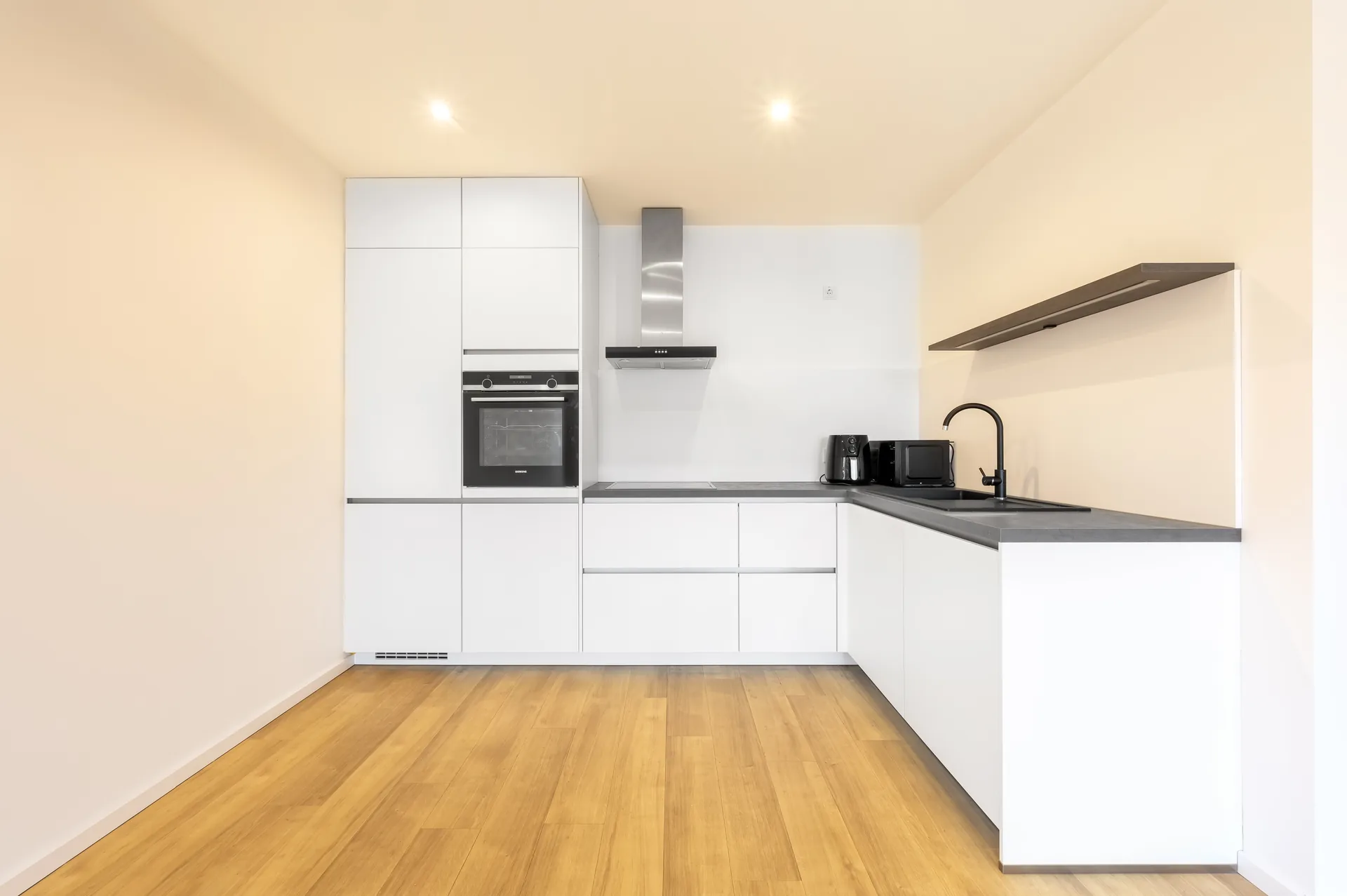 Moderne Einbauküche mit weißen Fronten und dunkler Arbeitsplatte im Lifestyle-Apartment, Neubau Mönchengladbach