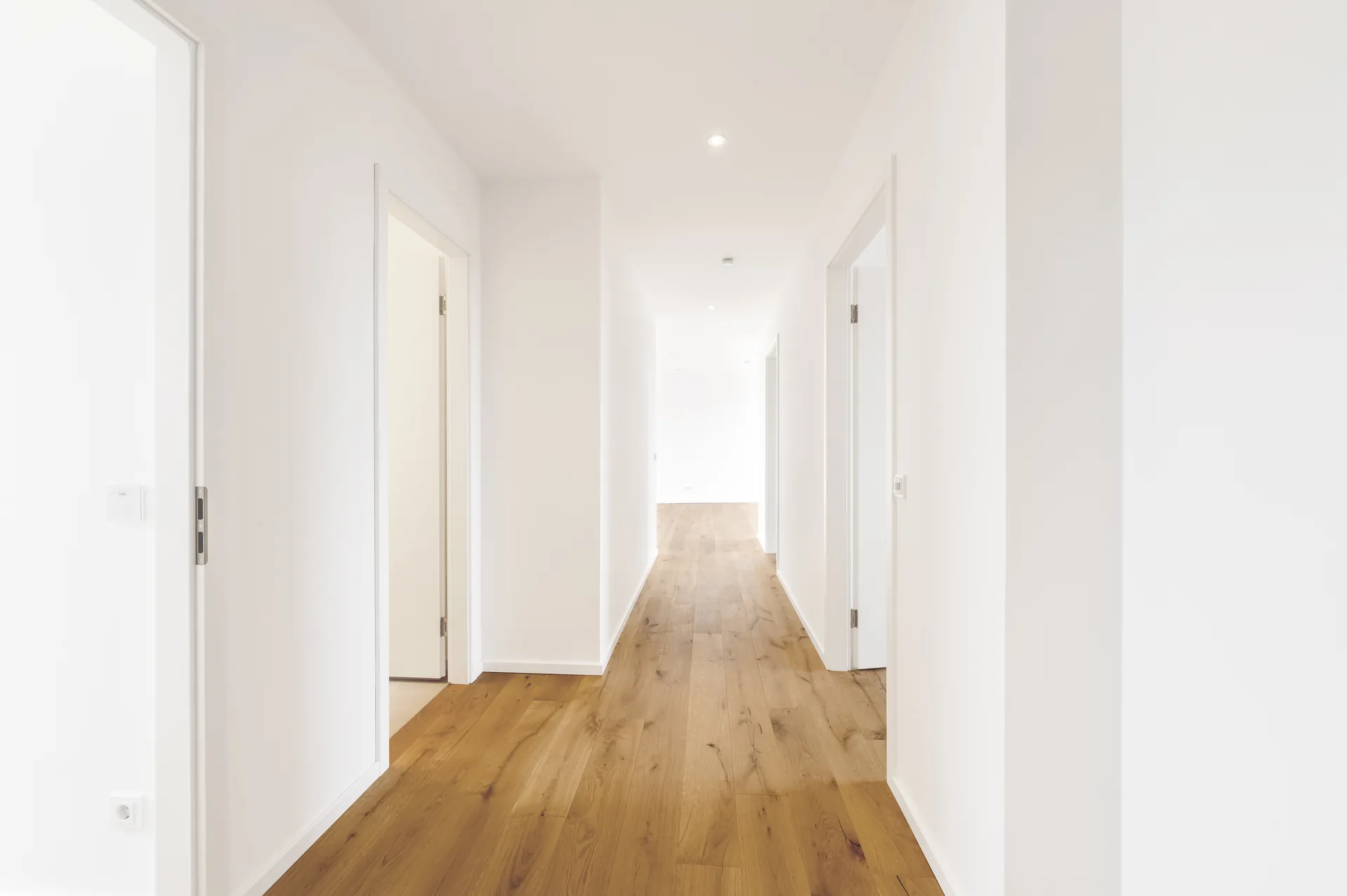 Langer heller Flur mit Echtholzparkett und mehreren Zimmertüren im Luxus-Penthouse, Quartier am Wasserturm