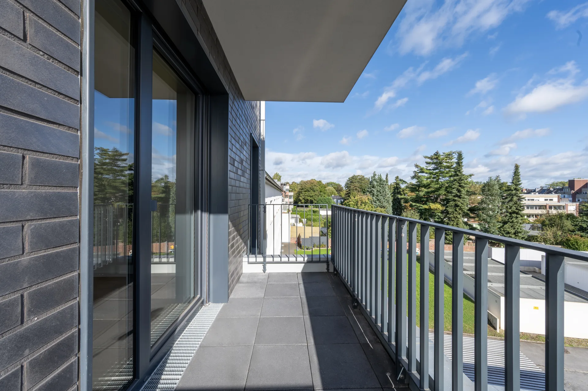 Sonniger Balkon mit Blick ins Grüne und anthrazitfarbener Fassade im Premium-Apartment, Quartier am Wasserturm