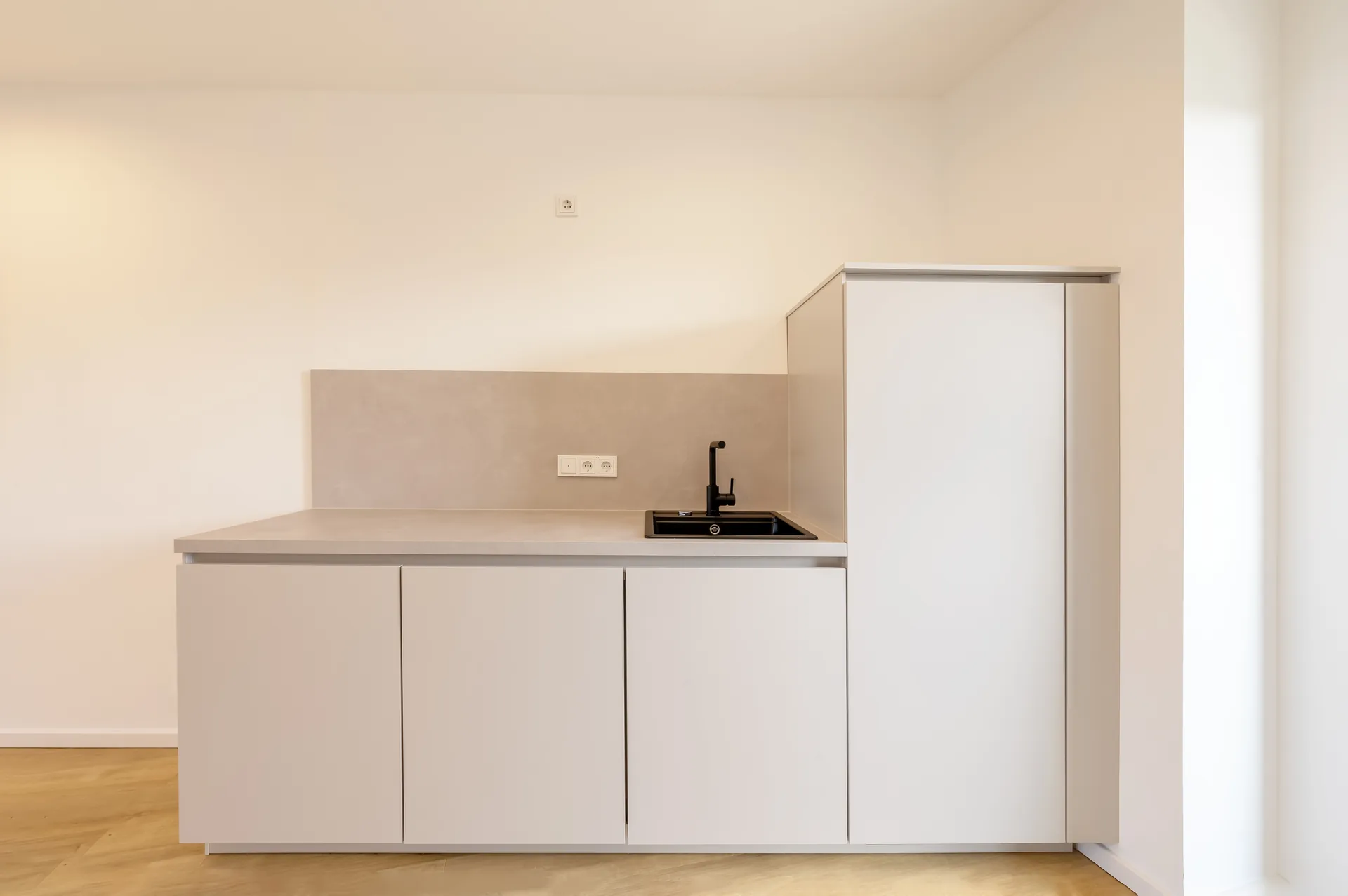 Moderne Einbauküche mit hellen Fronten und schwarzer Armatur im Premium-Apartment, Neubau Viersener Straße