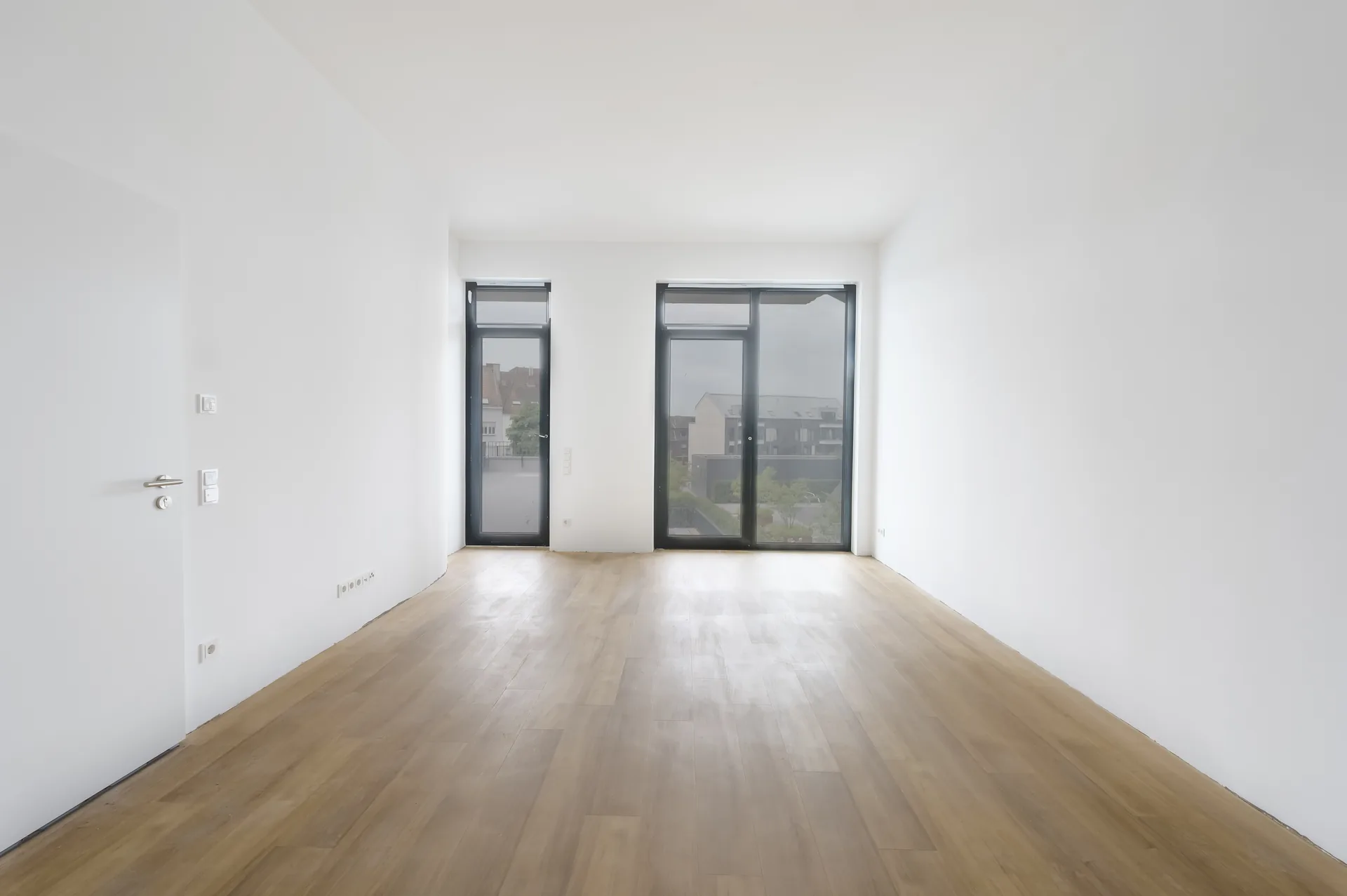 Helles Wohnzimmer mit bodentiefen Fenstern und Blick auf Mönchengladbach im 3-Zimmer-Premium-Apartment